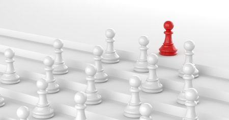 Red chess pawn standing apart from rows of identical white pawns, visually illustrating how a distinctive employee value proposition sets an organization apart in a competitive talent market.